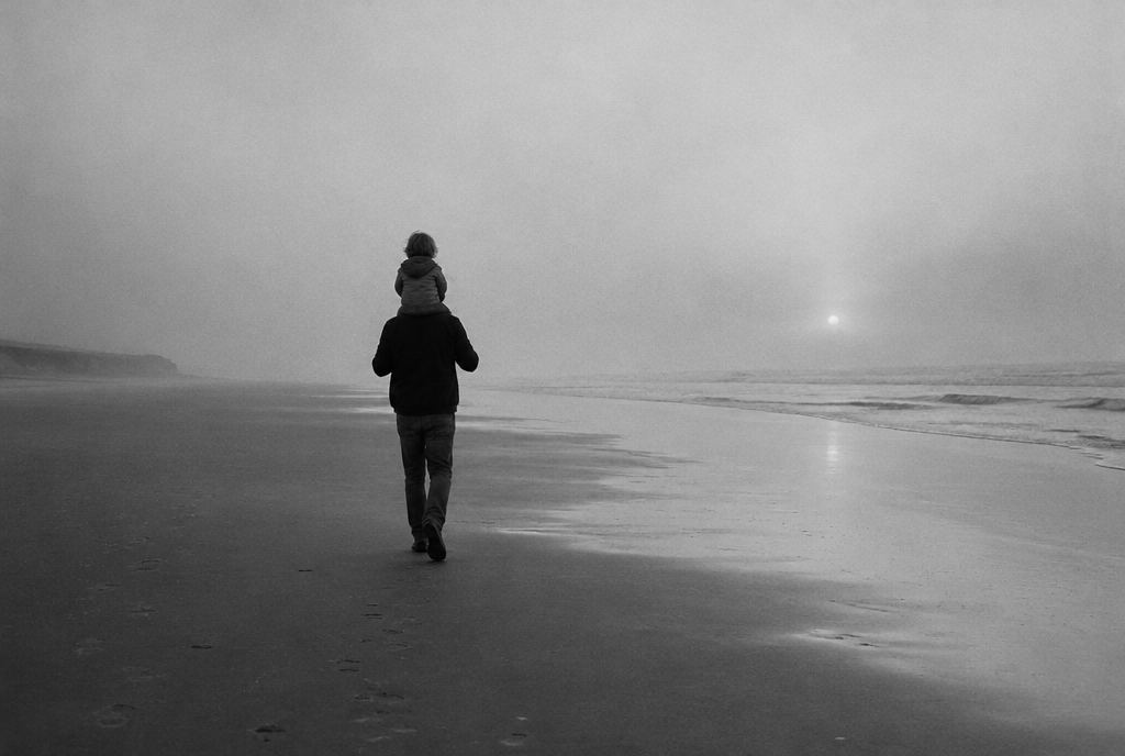 Un hombre camina por la playa con un niño en hombros